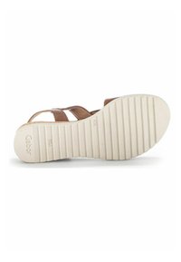 Bruine leren sandalen met kruiselingse banden, voorzien van een gestructureerde witte rubberen zool en een reliëf merklogo aan de onderkant.