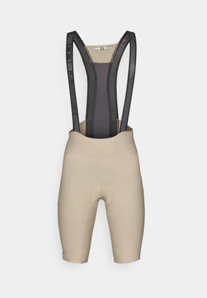 Beżowe spodenki rowerowe z czarnymi siateczkowymi szelkami, z podkładką w okolicy siedzenia oraz gładkim, elastycznym materiałem zapewniającym komfort i wsparcie.