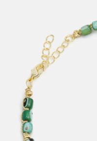 Gouden kettingarmband met groene en turquoise kralen met een gladde textuur en een karabijnsluiting. Opmerkelijke details zijn de gouden tussenstukken.