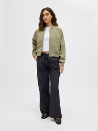 Olive green bomber jacket with a ribbed neckline, cropped design, paired with black wide-leg pants and black mesh slip-on shoes.