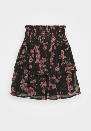 Svart lagerkjol med rosa blommönster och smockad midja, tillverkad av lätt genomskinlig tyg.