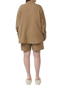 Beige, textuurshirt en bijpassende korte broek van lichtgewicht materiaal, met een relaxte pasvorm en een gebogen zoom.