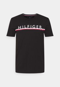 Camiseta de algodón negra con mangas cortas, cuello redondo y el logo "HILFIGER" en el pecho, con un acento de rayas rojas y blancas.