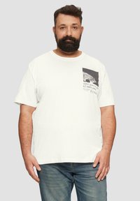 Witte katoenen t-shirt met korte mouwen, voorzien van een zwart-wit grafische zakprint en een casual pasvorm. Combinatie met blauwe denim jeans.