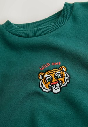 Green sweatshirt featuring a round ribbed neckline. Embroidered orange and white tiger face with green eyes and "WILD ONE" text above.