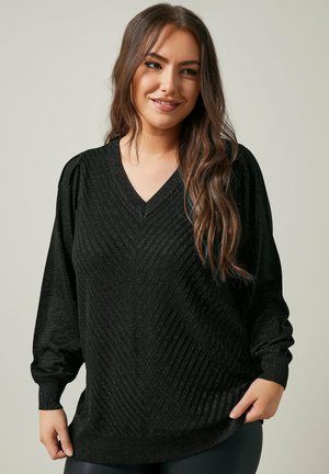 Pull noir à col en V, présentant des motifs chevron texturés et un matériau en tricot doux et légèrement brillant. Manches à coupe ample.