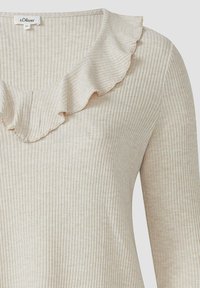 Beige geripptes Langarmoberteil mit V-Ausschnitt und einer wellenförmigen Rüsche am Kragen. Der Stoff hat eine weiche Textur mit dezentem Glanz.