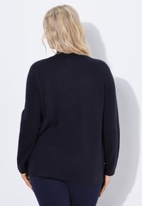 Maglione navy con maniche lunghe, vestibilità rilassata, texture morbida e orlo curvo. Progettato per il comfort con una silhouette semplice e classica.