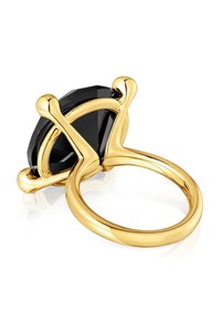 Anillo dorado con una gran piedra negra facetada sujeta por un engaste de cuatro garras. Banda lisa y brillante con bordes redondeados y un diseño minimalista.