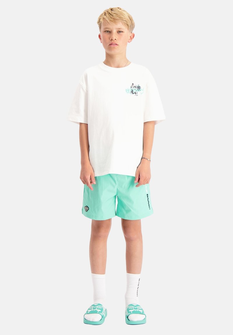 Witte katoenen t-shirt met grafisch ontwerp op de borst, gecombineerd met mintgroene zwembroek. Accessoires omvatten witte sokken en teal instappers.