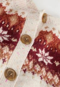 Wollcardigan mit einem cremefarbenen Grundton und roten, braunen sowie rosa Schneeflockenmustern; braune Knöpfe und ein gerippter Kragen verleihen Textur.