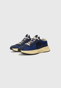 Navy blue sneakers featuring a mix of suede and mesh materials, textured laces, black accents, and a beige rubber outsole.