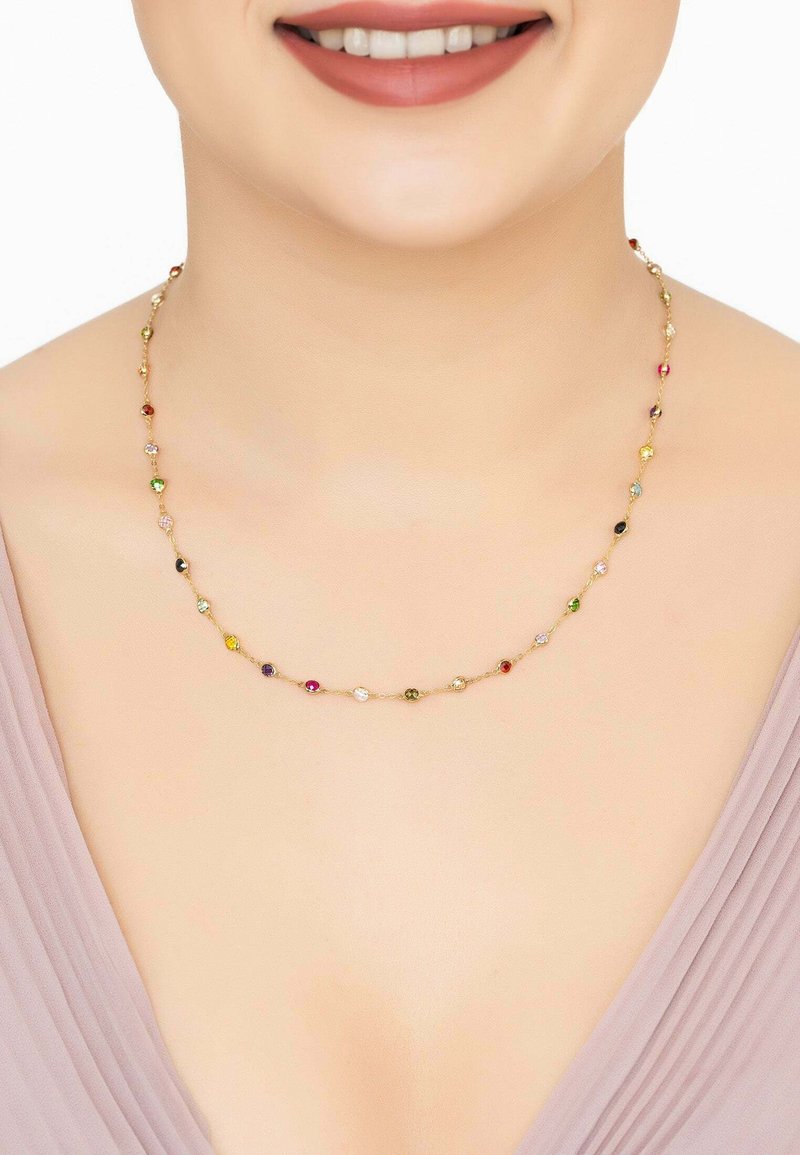 Gold necklace featuring multicolored crystal beads in various shapes, smoothly reflecting light, worn against a neutral skin tone.