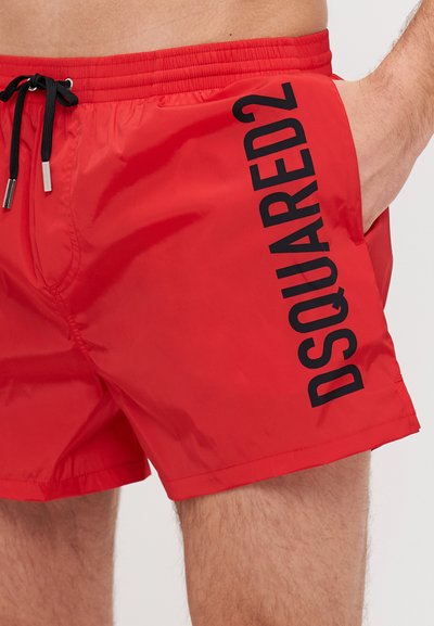 Costume de baie roșu cu talie elastică și șnur negru, având un mare logo vertical "DSQUARED2" pe partea stângă.