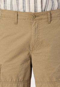 Kaki cargo šortsevi s kopčanjem na dugme, s ravnim strukom, bočnim džepovima i šivenim detaljima. Izdržljiv pamučni materijal.