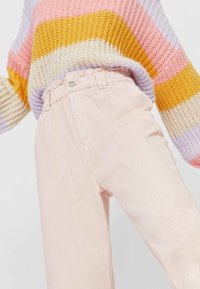 Stickad tröja med flerfärgade ränder i rosa, gult och lavendel, i kombination med lätta rosa, högmidjade byxor med elastiskt midjeband.