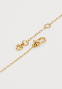 Guldkedjearmband med ett hjärtformigt berlock, krabba-lås, cirkulära länkar och en texturerad yta. Perfekt för att bära lager på lager eller som ett fristående smycke.