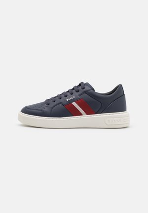 Donkerblauwe leren sneaker met rode en witte strepen aan de zijkant, witte zool, veterluiting aan de voorkant en "BALLY"-logo aan de zijkant en onderkant.