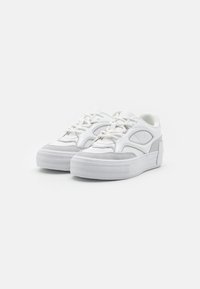 Weiße Sneaker mit einem strukturierten grauen Wildledereinsatz, runder Zehenpartie, dicke Plattformsohle, Schnürverschluss und einem markanten Ausschnittdesign.