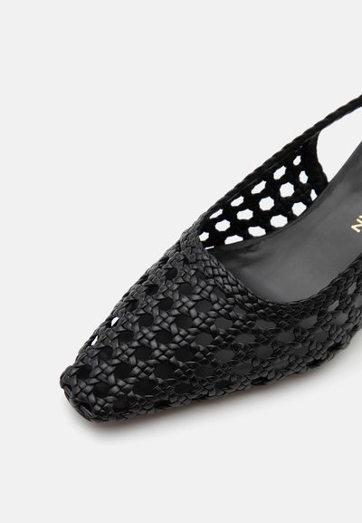 Chaussure plate en cuir tressé noir à bout pointu, motif hexagonal ouvert et aérien sur la tige et doublure intérieure lisse.