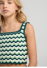 Top corto de crochet con un patrón ondulado en verde, blanco y verde oscuro. Presenta un escote cuadrado y un dobladillo con borde festoneado. Detalle de botones en el lateral.