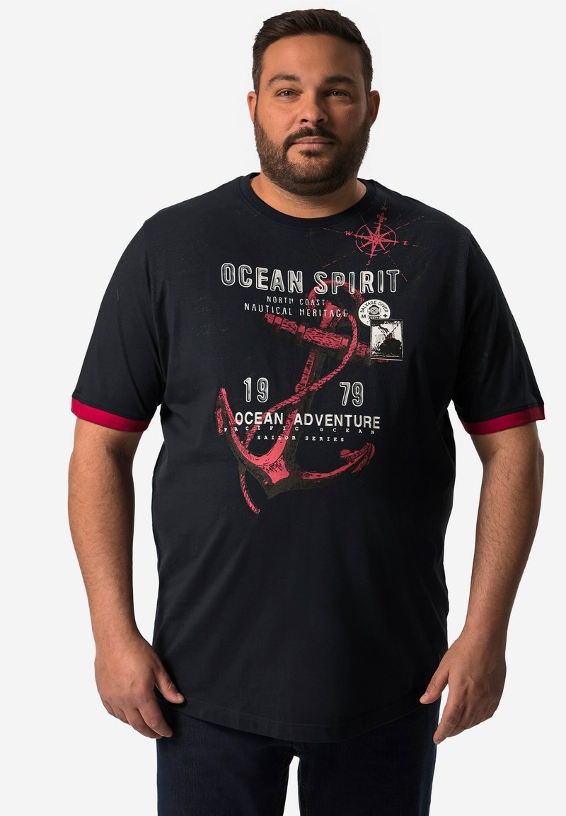 Černé tričko s krátkým rukávem a červenými akcenty, s námořnickými grafikami, včetně kotvy a kompasu, označené "OCEAN SPIRIT."