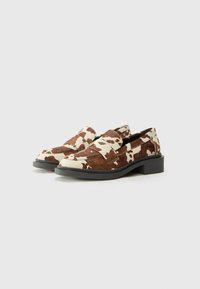 Brown and white cowhide-patterned loafers with a low black heel and visible stitching detail. Smooth texture with a rounded toe.