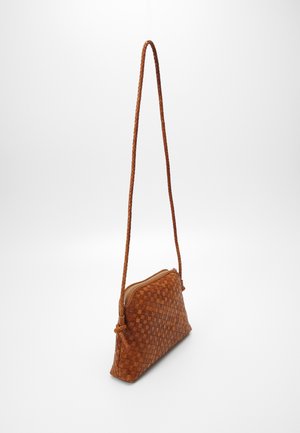 Woven leather crossbody bag in warm brown, featuring a long braided strap and zip closure, with a structured, triangular shape.