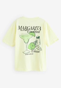 Kollane puuvillane T-särk, millel on kokteili graafika, kus on margarita klaas, laim, soolakann ja tekst "MARGARITA Classic."