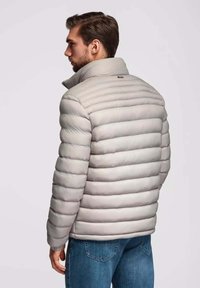 Hellgraue Steppjacke mit hohem Kragen, horizontalen Nähten und elastischen Bündchen. Weiche Textur und isoliertes Design für Wärme.