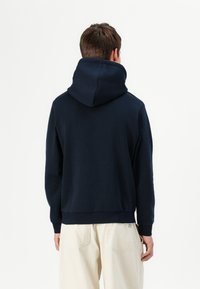 Navy blue hoodie with a large hood, ribbed cuffs and hem, made from soft fabric. Simple design with no visible logos or patterns.