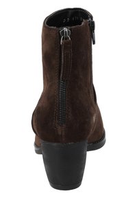 Botín de ante marrón hasta el tobillo con punta redonda y tacón negro apilado. Cuenta con una cremallera lateral para facilitar el uso y un sutil detalle de costura.