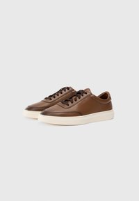 Brune lær sneakers med et glat design, rund tå, mørkebrune snørebånd og en cremefarvet gummisål med diskret branding.
