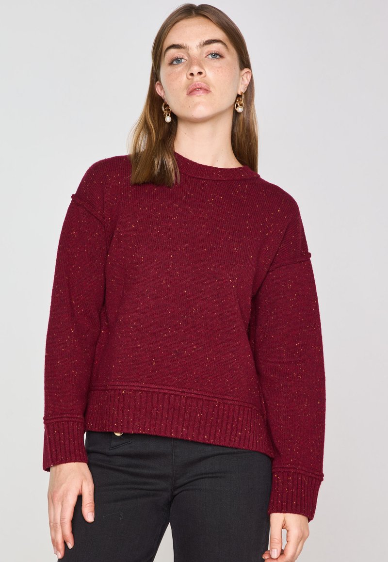 Maglione a maglia color bordeaux con orlo e polsini a coste, caratterizzato da fili di colore sparsi. Progettato con una vestibilità comoda e scollatura rotonda.