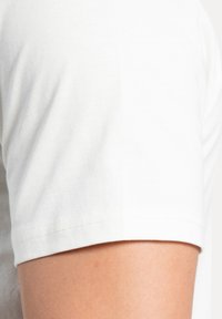 Hvid bomulds T-shirt med korte ærmer, der har en glat overflade og et enkelt design. Kanten er pænt syet.