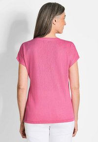 Rosa Kurzarmtop mit lässigem Schnitt, rundem Halsausschnitt und schlichter Textur. Der Rücken hat einen Saum, der knapp über den Hüften endet.