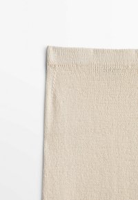 Beige gebreide stof, met een textuurafwerking en een gladde, egale weefsel. De randen vertonen een nette, omgevouwen zoomontwerp.