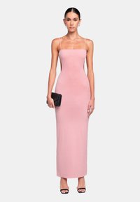 Robe maxi rose ajustée à côtes avec des fines bretelles et un décolleté droit. Portée avec une pochette noire et des talons ouverts noirs.
