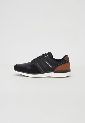 Black athletic shoe with synthetic and textile materials. Features a textured finish, brown accents, and a white rubber sole. Lace-up design.