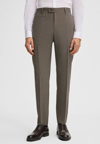Spodnie w kolorze brązowym, dopasowane, z delikatnym wzorem w kratę, prostym krojem, szlufkami na pasek i bocznymi kieszeniami. Noszone z czarnymi, eleganckimi, wypolerowanymi butami.