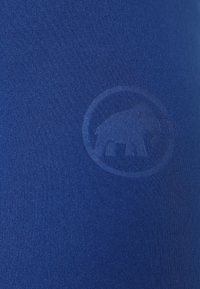 Tessuto blu con una superficie liscia, caratterizzato da un logo a forma di elefante goffrato in modo sottile in un design circolare.