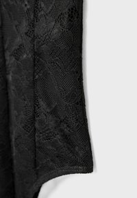 Črna čipkasta tkanina s cvetličnimi vzorci in mehko teksturo, ki ima valovito robno obrobo in podrobne mrežaste sekcije.