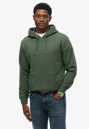 Green cotton hoodie with a front pocket, adjustable drawstring hood, and ribbed cuffs. Paired with blue jeans and a watch.