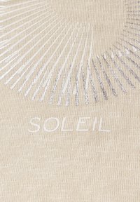 Tessuto beige con grafica a raggi di sole. Testo chiaro con la scritta "SOLEIL" in evidenza al centro, con accenti metallici.
