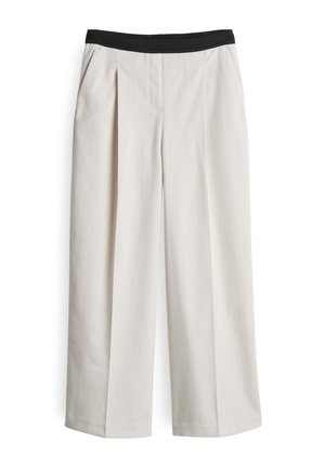 Wijdvallende broek van lichtbeige stof, met een geplooide voorkant en een zwarte elastische tailleband. Soepele textuur met fijne strepen.