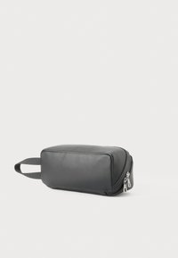 Sort, rektangulær kosmetikpung lavet af tekstureret læder, med lynlås lukning og et sideløkke til nem transport.