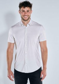 Kurzärmliges, knöpfbares Hemd in hellbeige mit subtilen Punkten, aus glattem Stoff gefertigt, mit Kragen und geradem Saum.