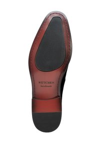 Schwarze Ledersohle mit roten Akzenten, ausgestattet mit einer strukturierten Gummisohle, auffälligen Nähten und dem eingeprägten Logo "Wittchen handmade".