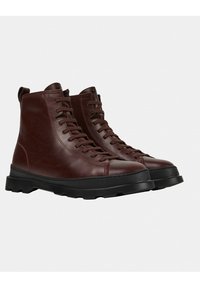 Brązowe skórzane buty za kostkę z wiązaniem, z wysoką cholewką, teksturowaną powierzchnią, gumową podeszwą oraz przeszyciami, które zapewniają trwałość i przyczepność.