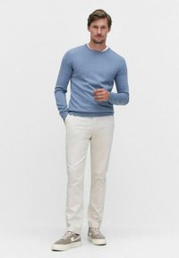 Ljusblå tröja, vita byxor och grå sneakers. Tröjan har rund halsringning, åtsittande ärmar och en slät textur. Avslappnad outfit.